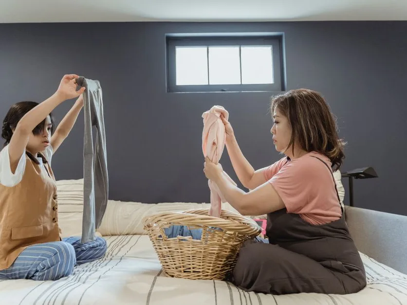 Une mère et sa fille plient le linge sur un lit